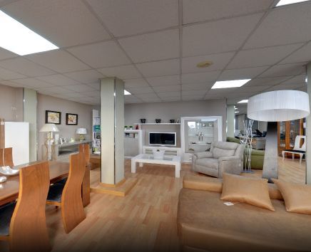 Amplia sala de exposición con muebles en exposición. Suelos de madera, paredes blancas e iluminación cenital brillante.