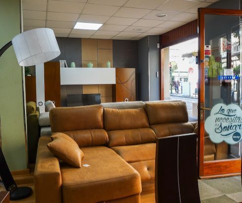 Tienda de muebles de interior, que presenta un sofá seccional marrón con una chaise longue y una lámpara de pie.