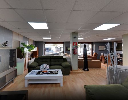 Interior de tienda de muebles con sofás, mesas y accesorios de iluminación.