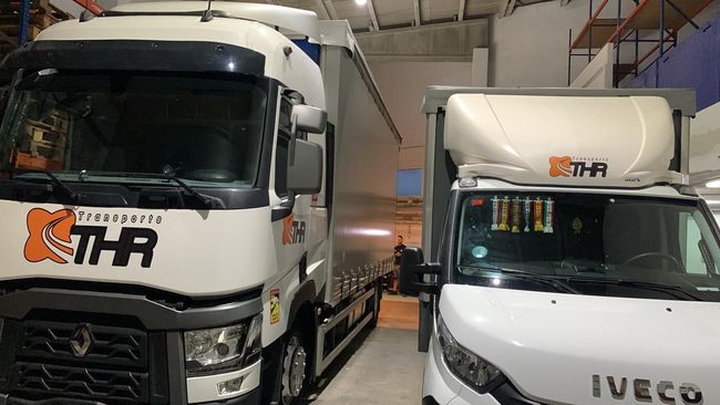Dos camiones están estacionados uno al lado del otro en un almacén.