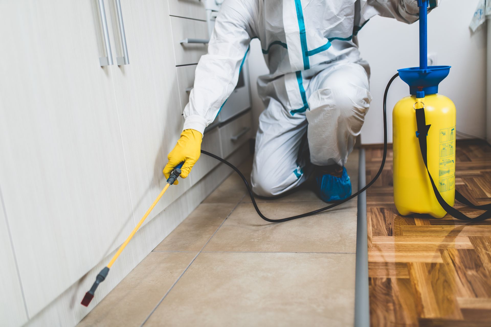 Un professionnel vêtu d'une combinaison de protection pulvérise un pesticide.