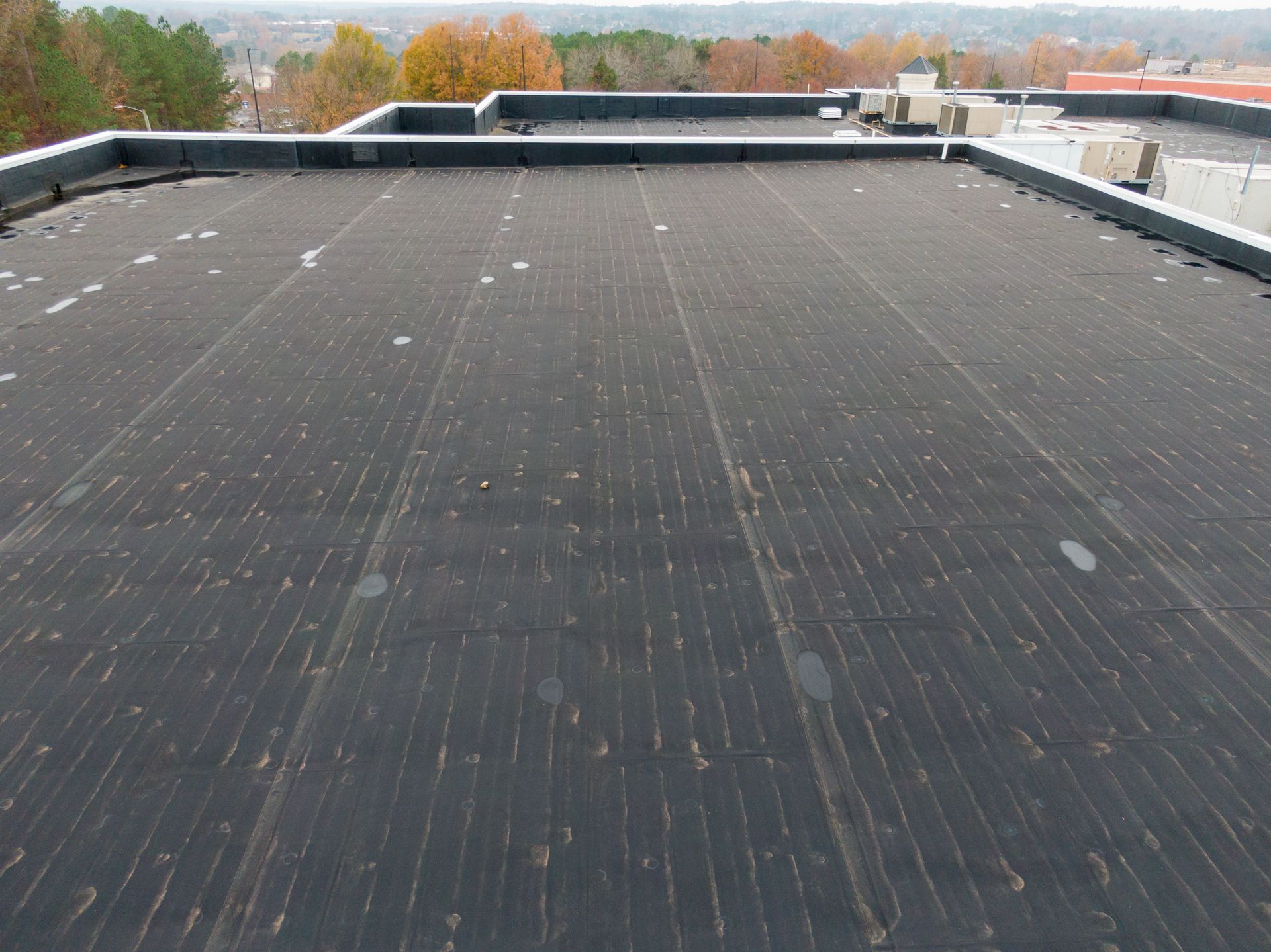 Une vaste surface de toiture commerciale plate et noire, avec des joints visibles, vue d'un angle élevé.
