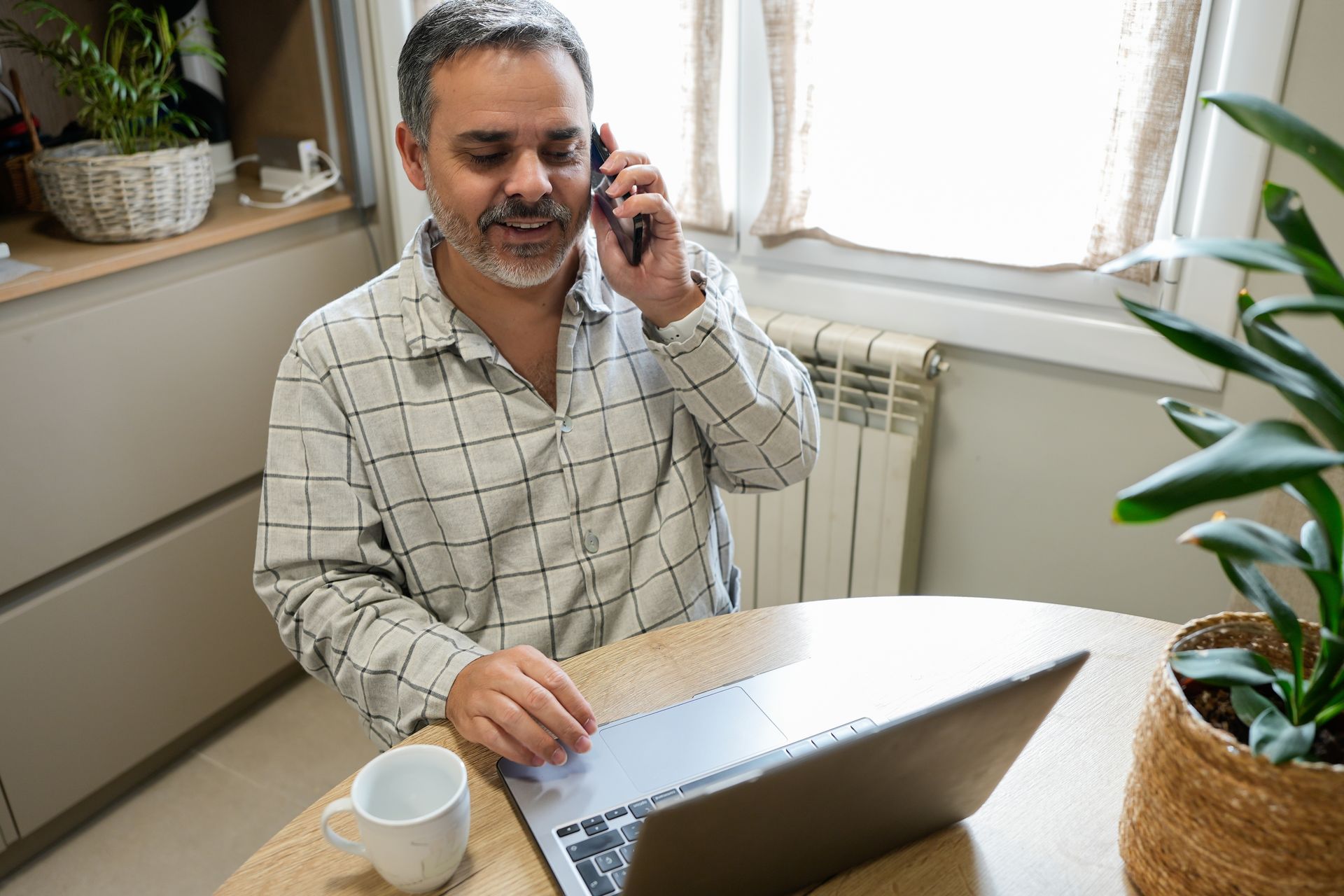 Mann mittleren Alters telefoniert zuhause mit seiner Schuldnerberatung