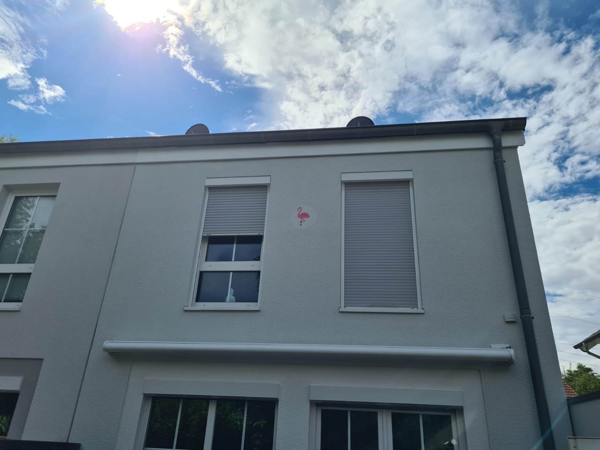 Ein weißes Gebäude mit vielen Fenstern und einem roten Pfeil, der nach rechts zeigt.