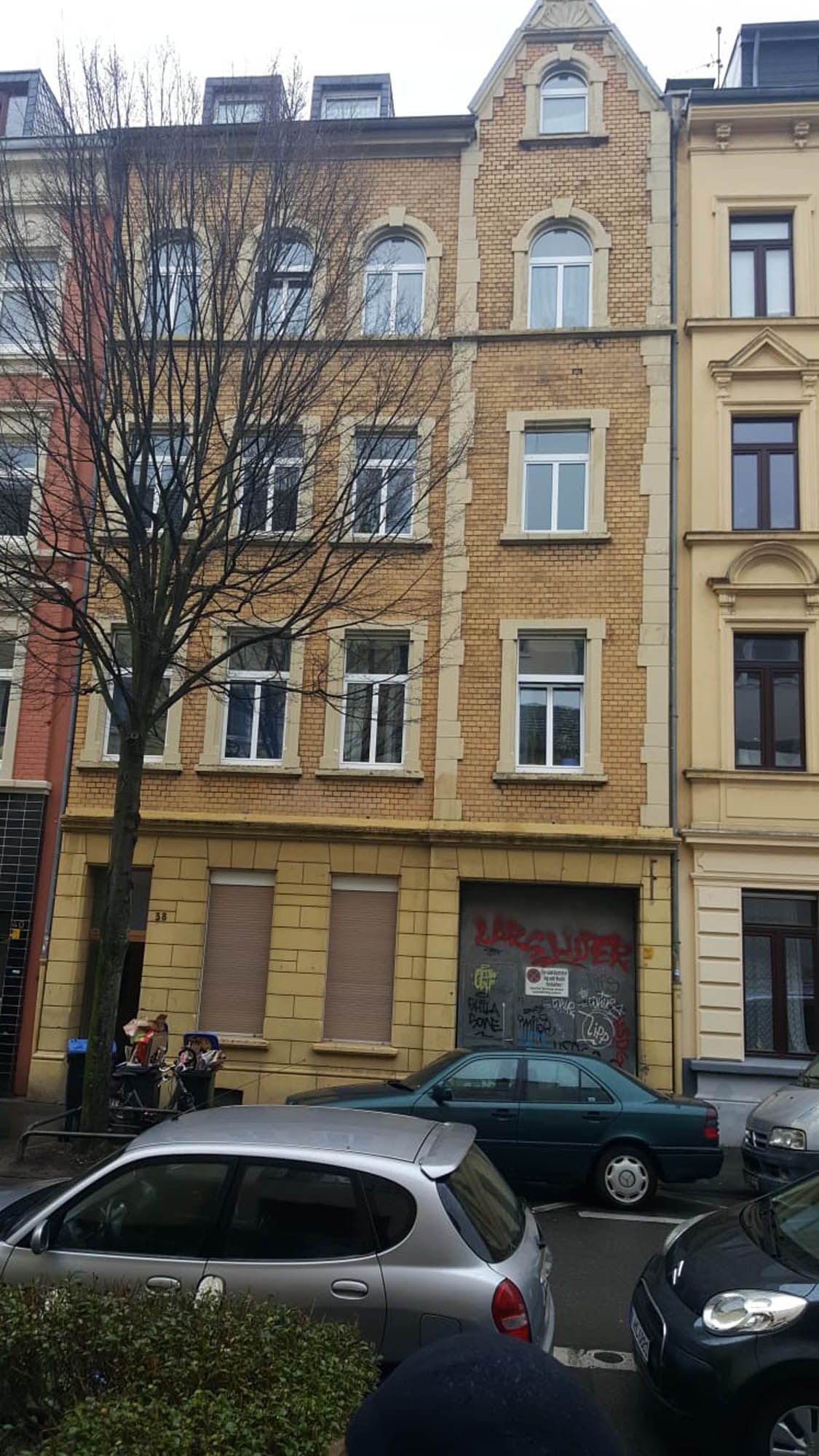 Ein Gebäude mit vielen Fenstern und davor geparkten Autos