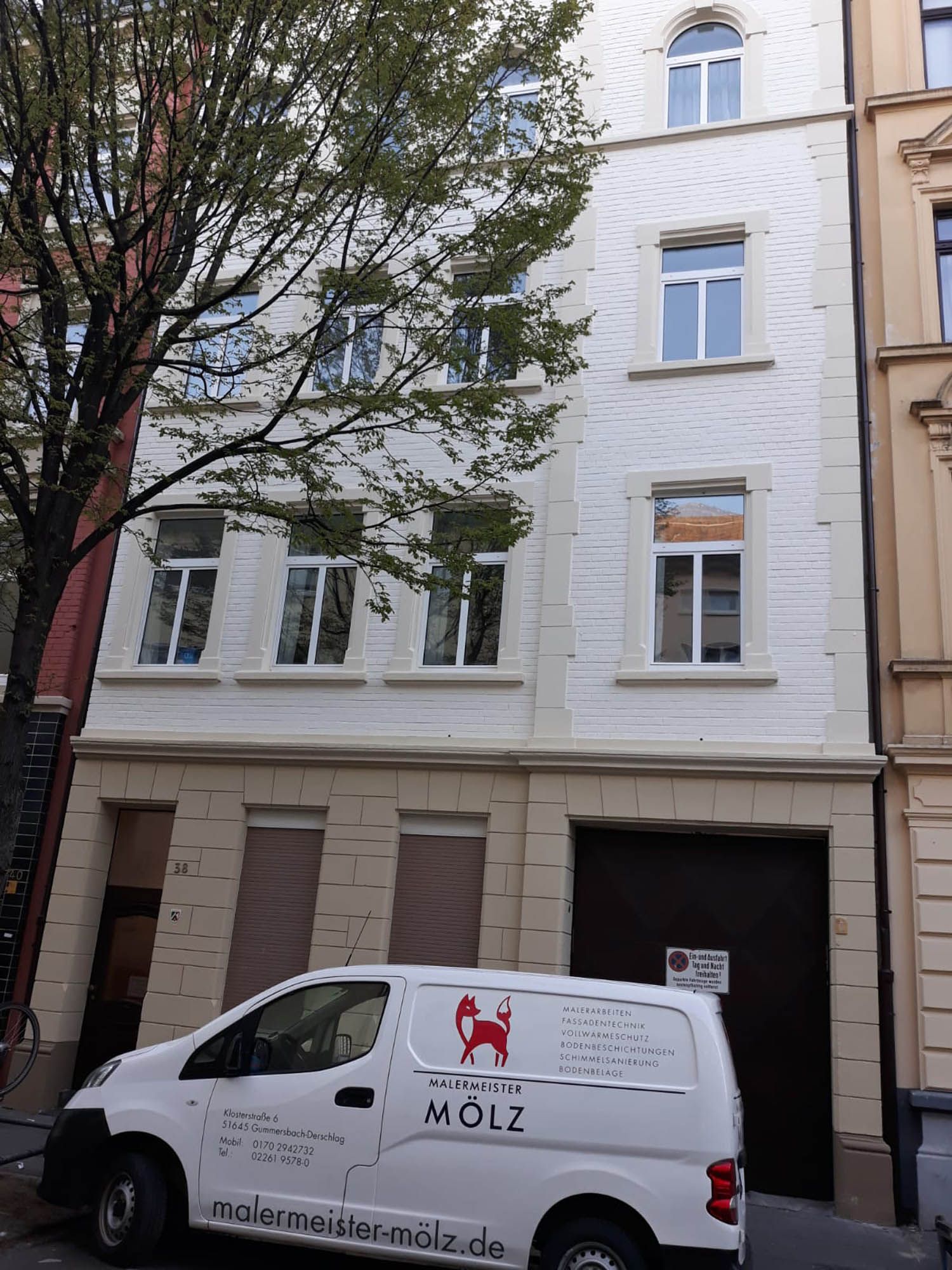 Ein weißer Lieferwagen mit dem Wort Molz auf der Seite steht vor einem Gebäude