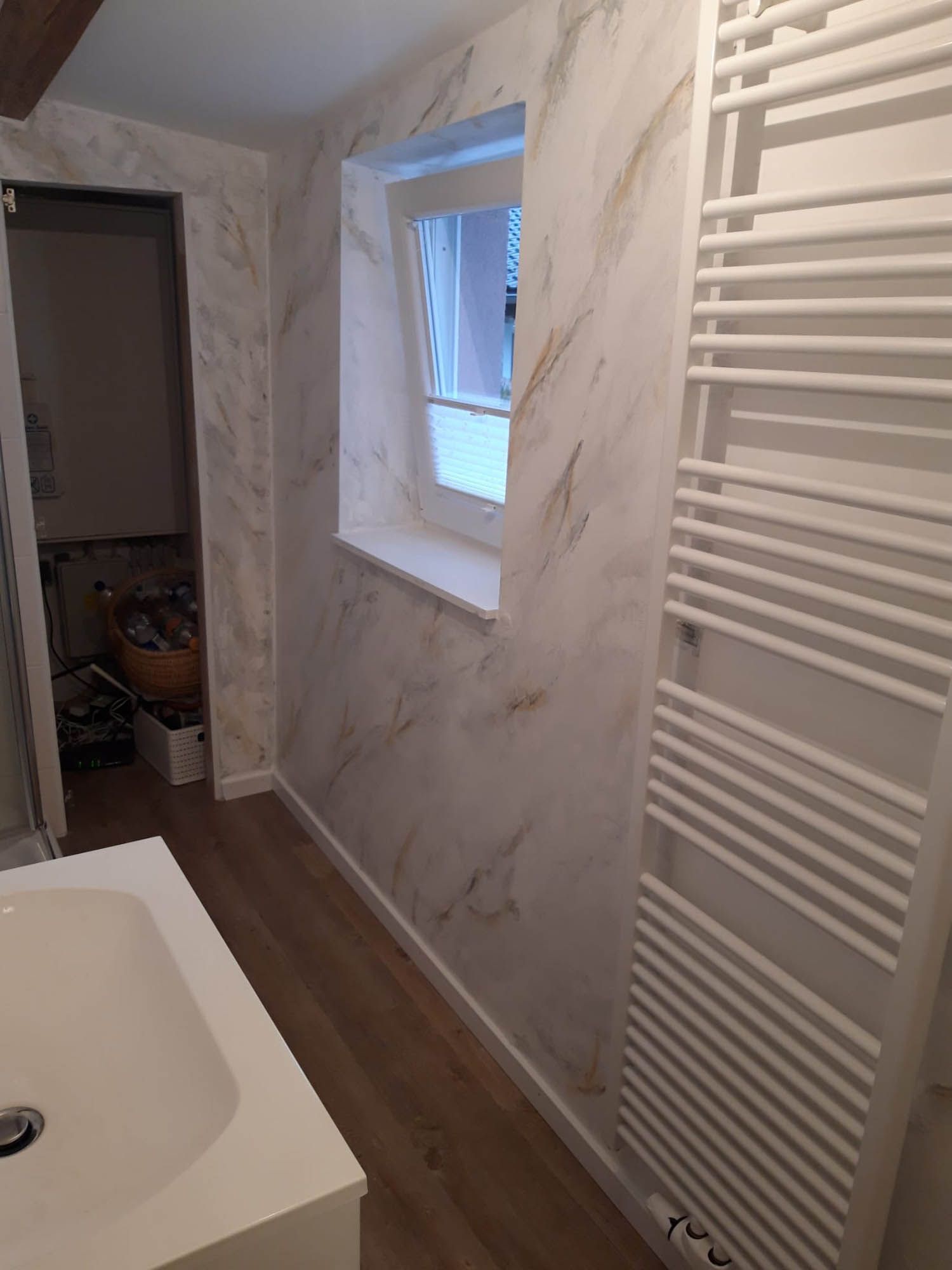 Ein Badezimmer mit Waschbecken, Handtuchhalter und Fenster.