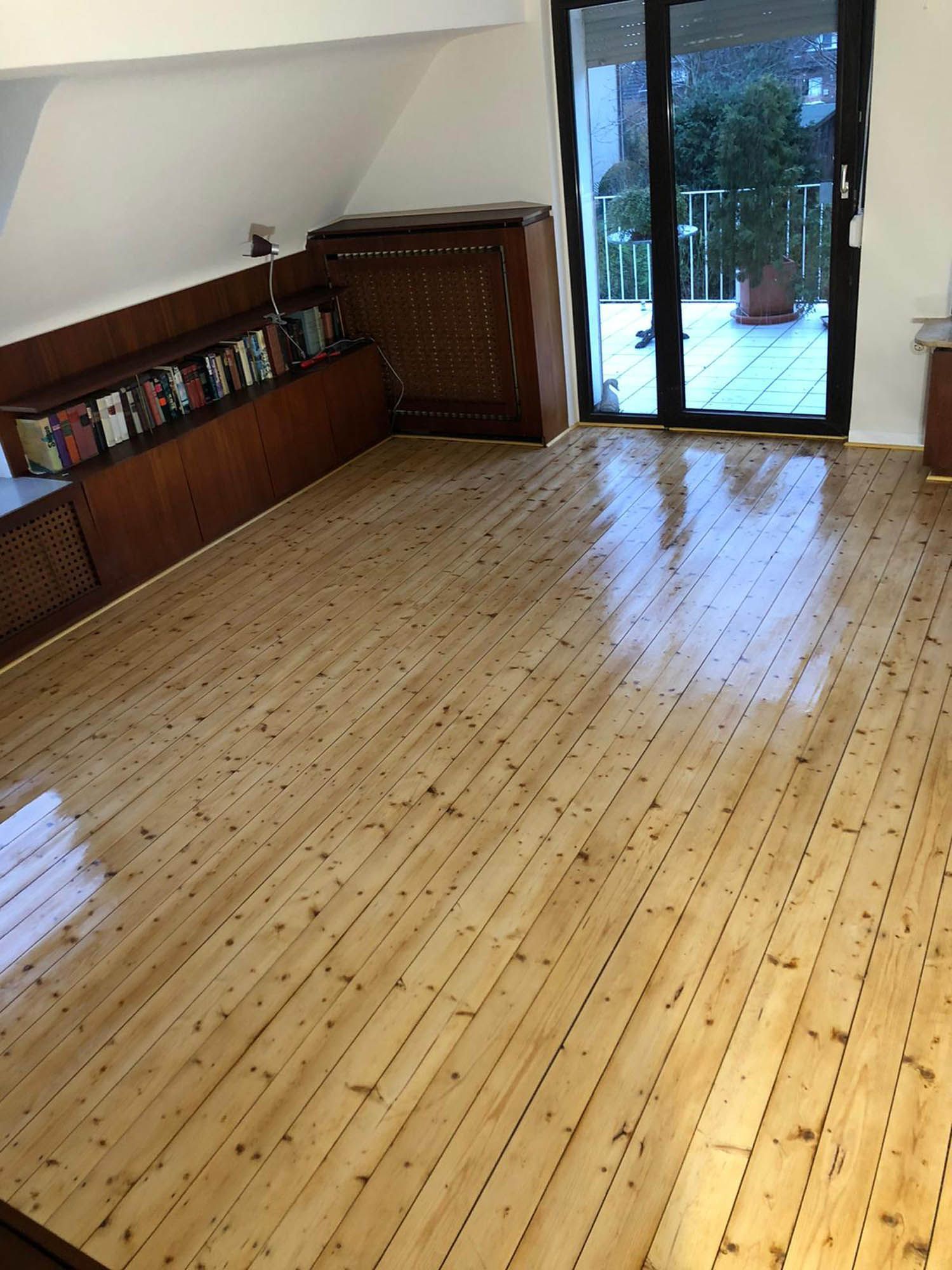 Ein Wohnzimmer mit Holzboden und Glasschiebetür.