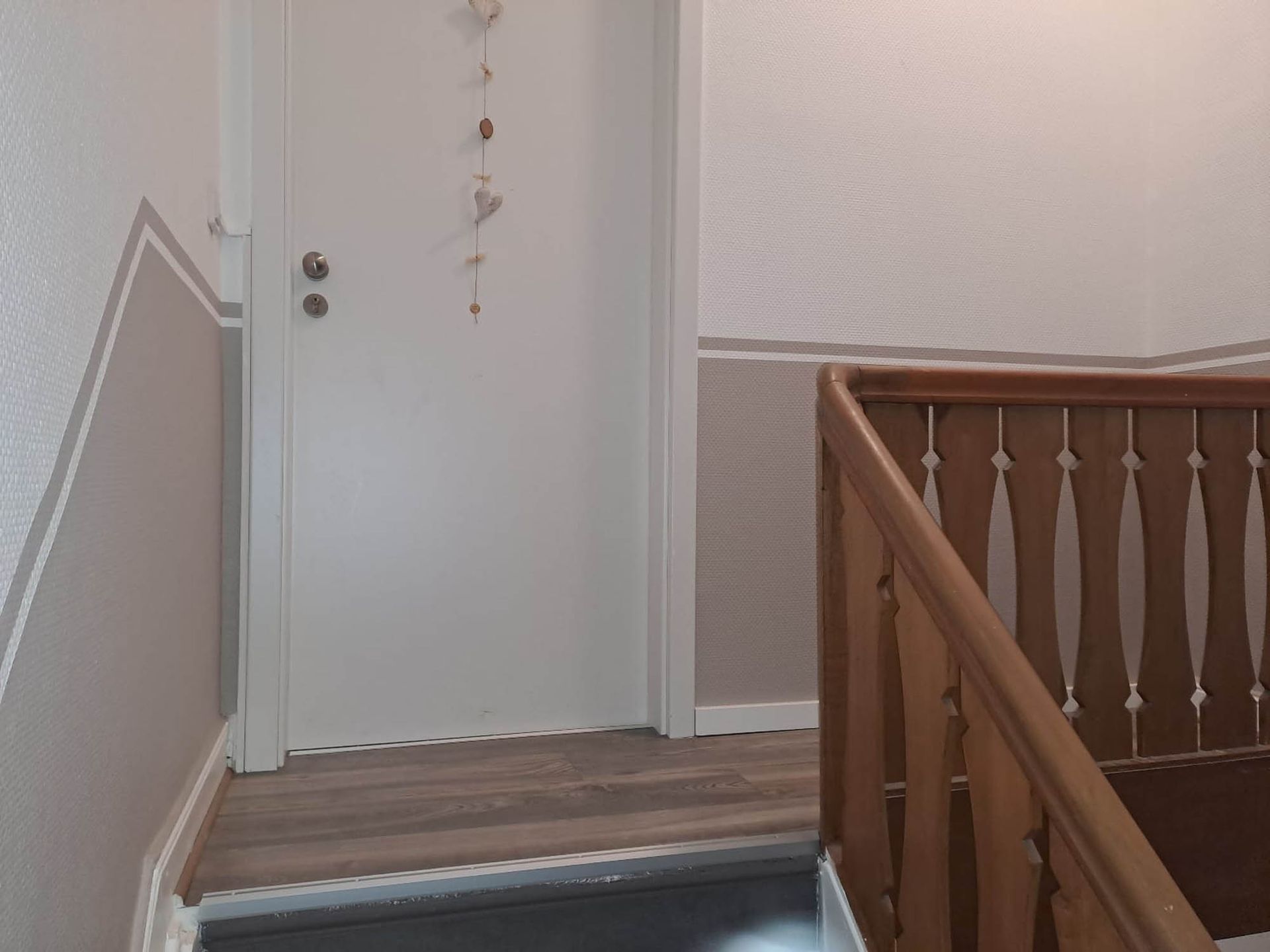 Ein Flur mit einem Holzgeländer und einer weißen Tür
