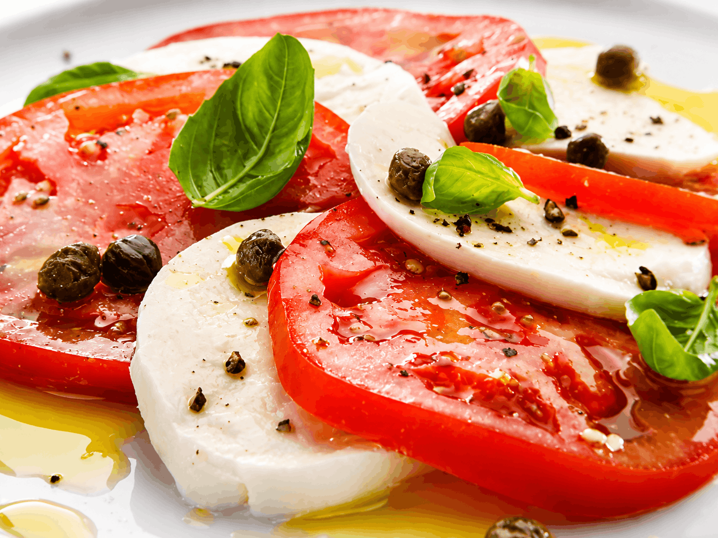 Σαλάτα Caprese με φέτες ντομάτας, μοτσαρέλα, φύλλα βασιλικού, ελαιόλαδο και μαύρο πιπέρι