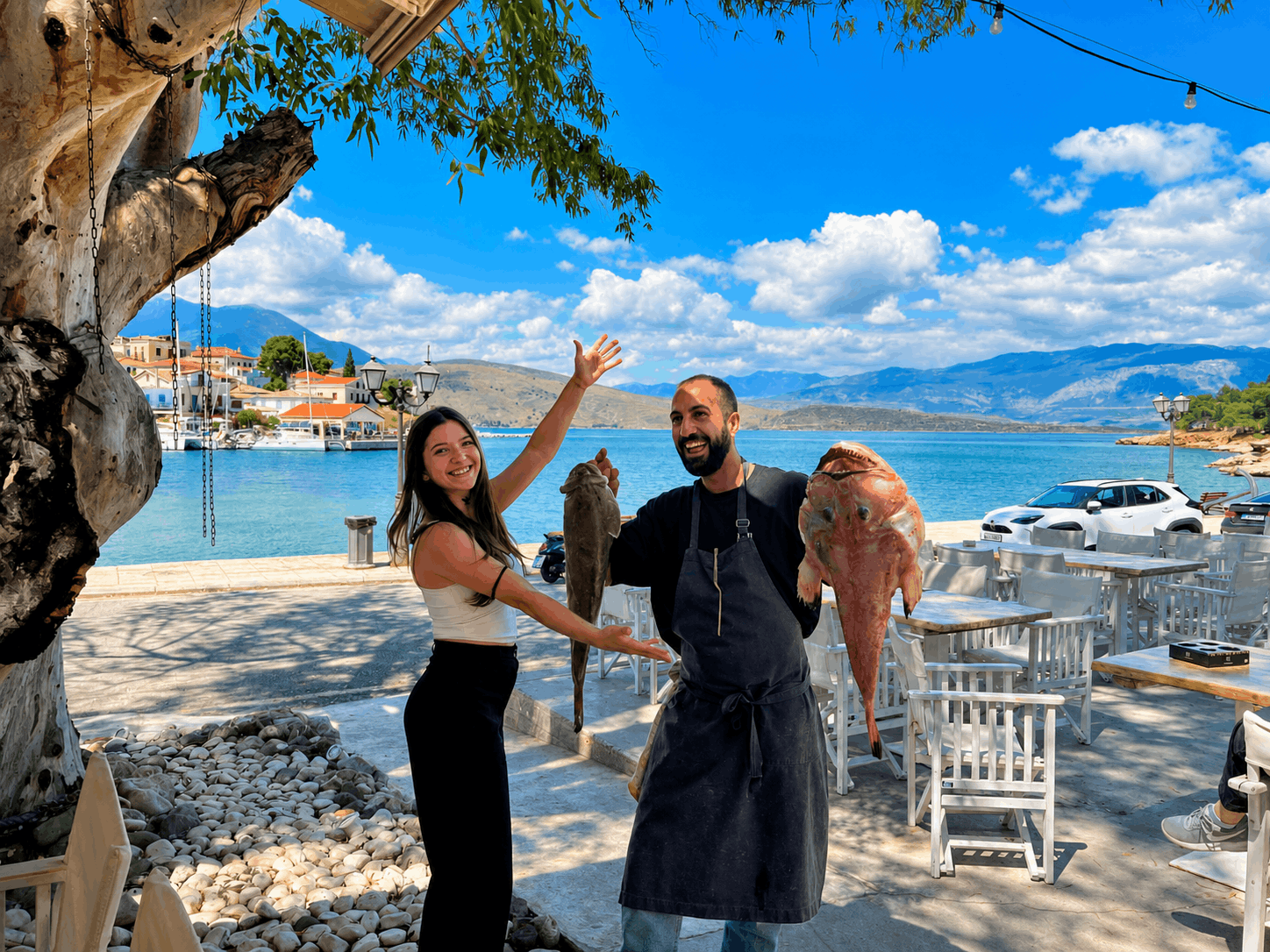 Τρία άτομα ποζάρουν δίπλα σε μια μαρίνα δίπλα στο νερό κάτω από ένα δέντρο μια ηλιόλουστη μέρα