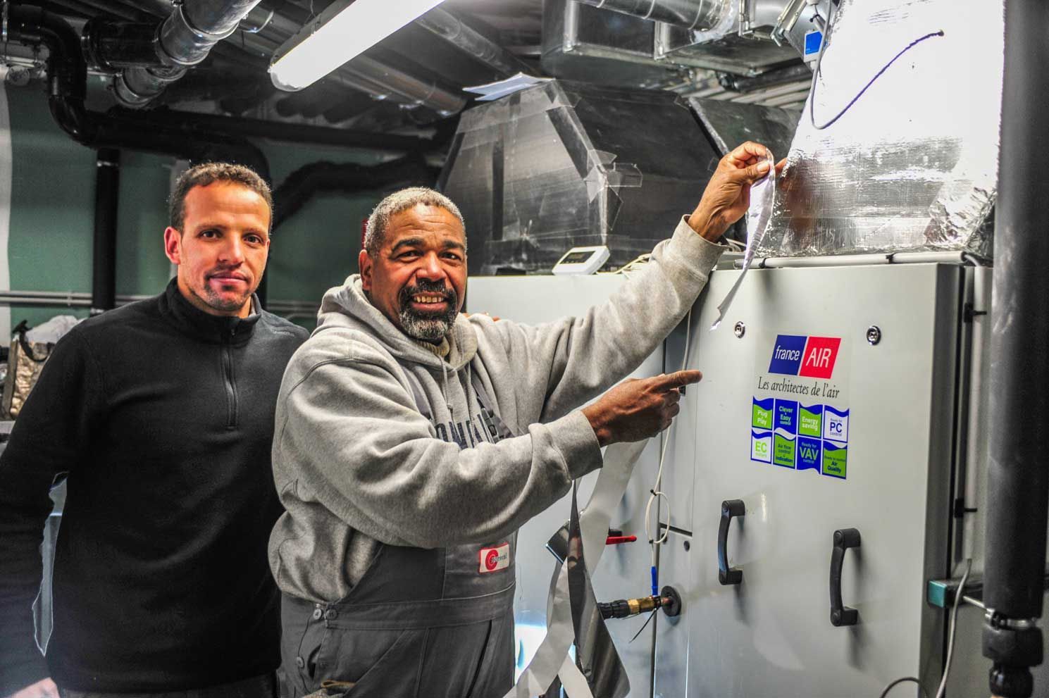 Deux experts en calorifugeage devant une unité de traitement de l'air mécanique