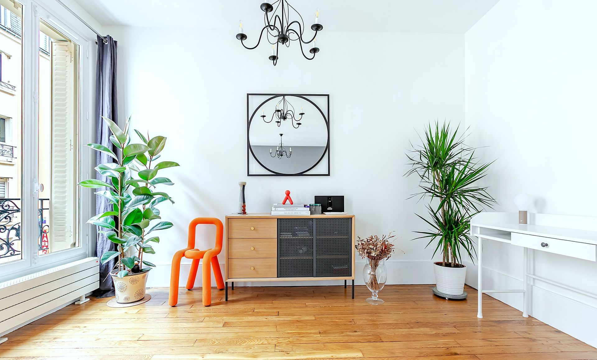 Salon moderne avec commode en bois, plantes et chaise orange