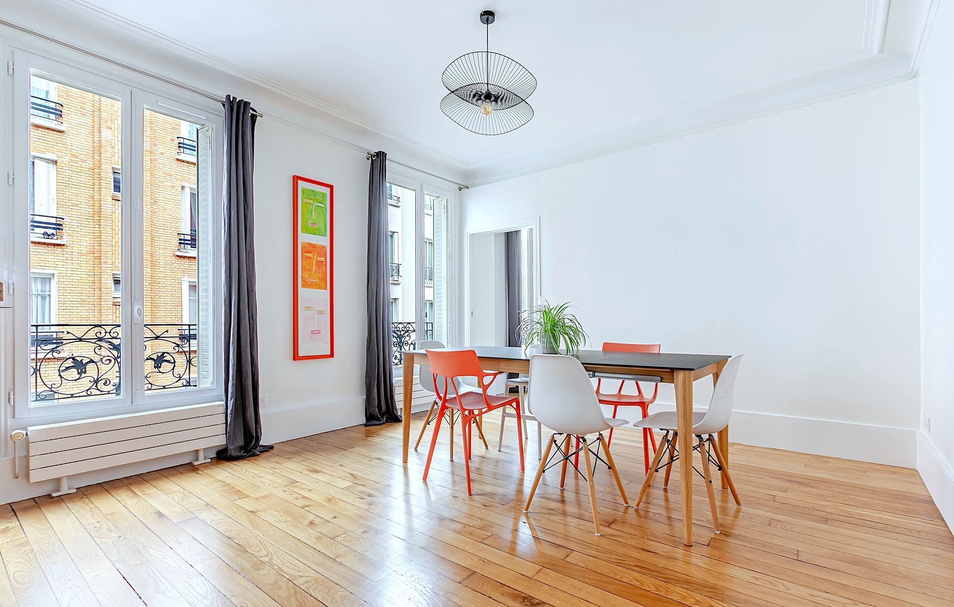 Couloir avec parquet, tapis à motifs et murs blancs ; une petite console est placée sous un miroir nuage.