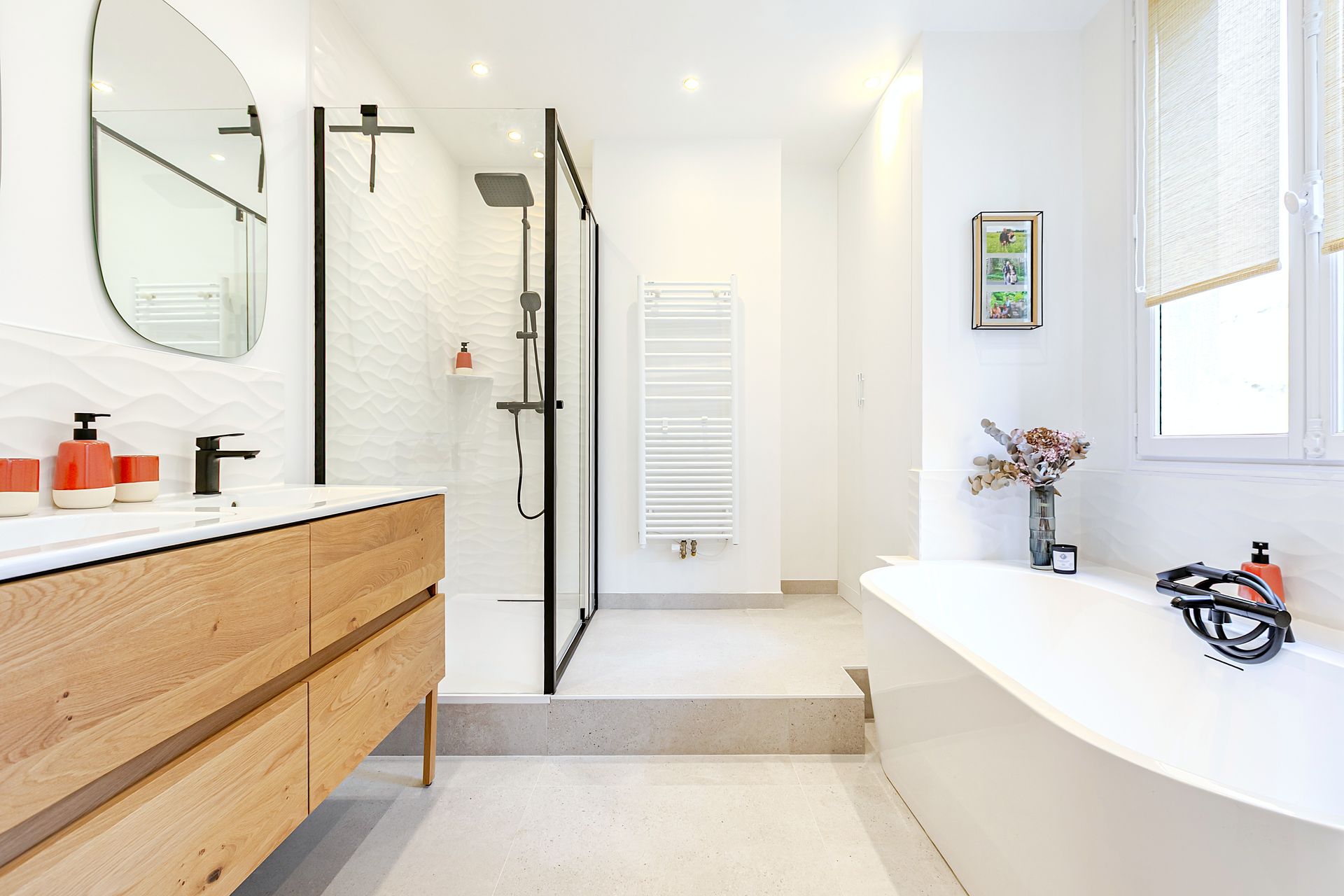 Salle de bains blanche moderne avec vanité en bois, douche en verre et baignoire autoportante.