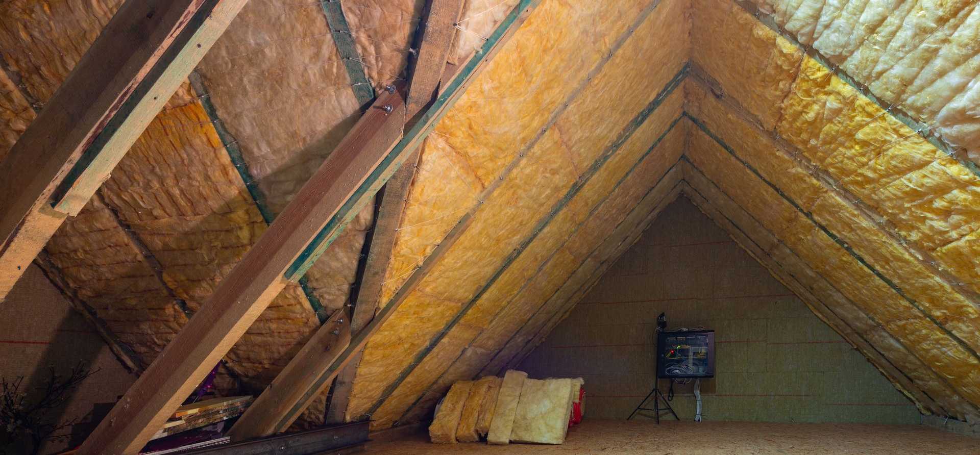 Vue intérieure d'un grenier avec poutres apparentes, isolation et petit électroménager.