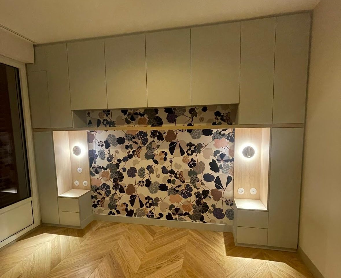 Tête de lit intégrée avec mur d'accent à motifs, rangement et appliques; armoires vert clair, plancher en bois.