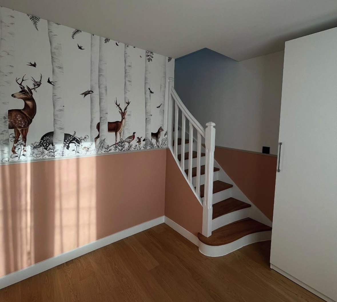 Chambre avec papier peint boisé, un escalier et un placard.