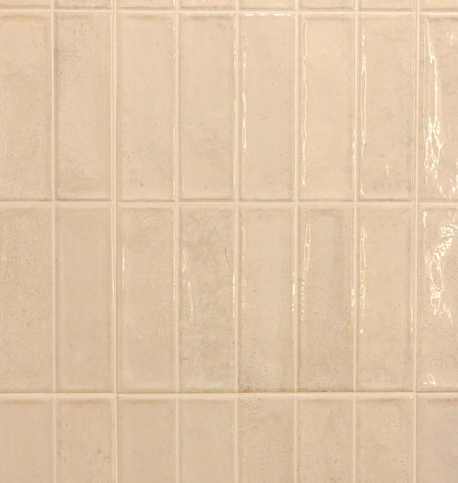 Carreaux rectangulaires beiges disposés en rangées verticales.