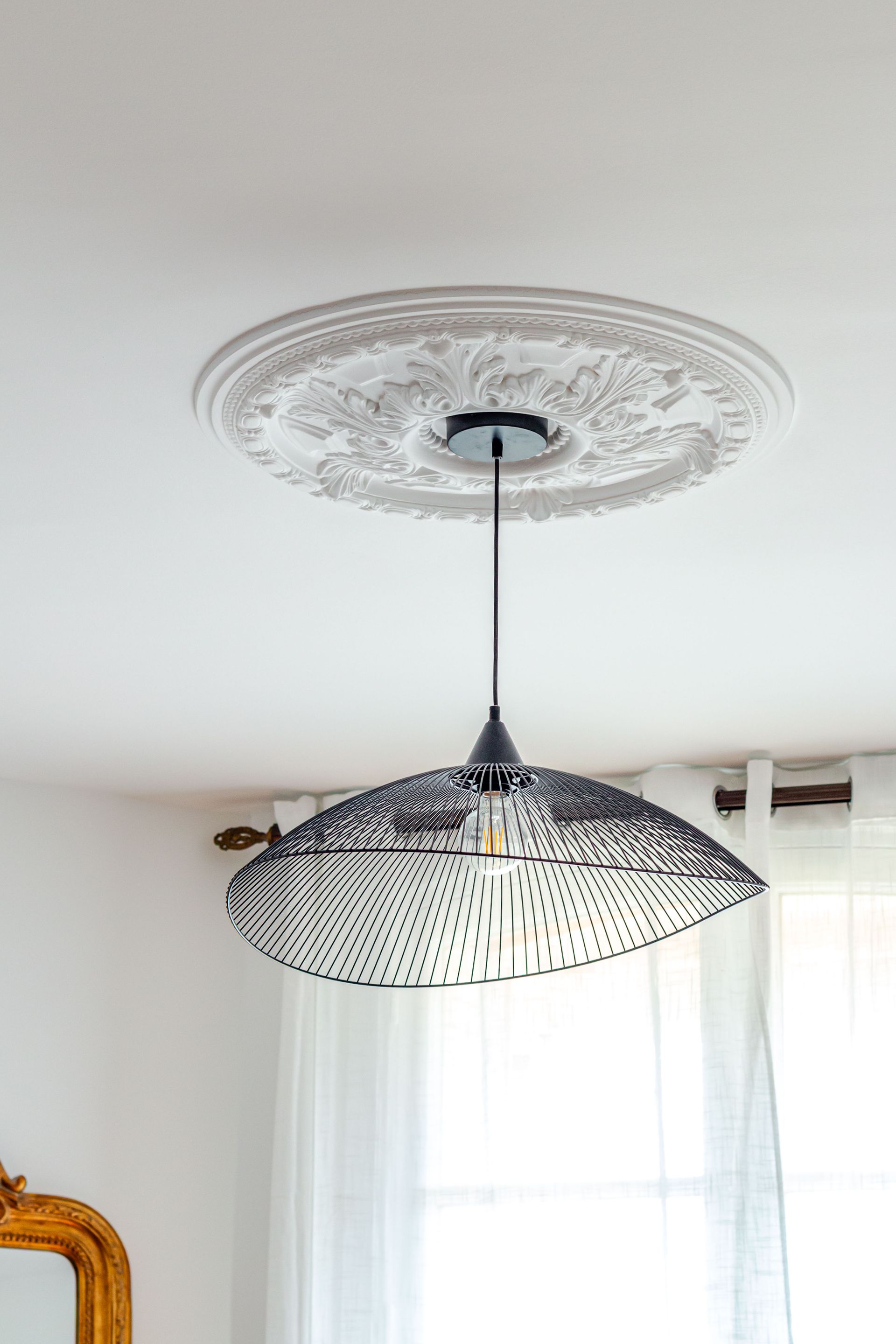 Suspension de plafond avec abat-jour décoratif, suspendue à un médaillon de plafond blanc.