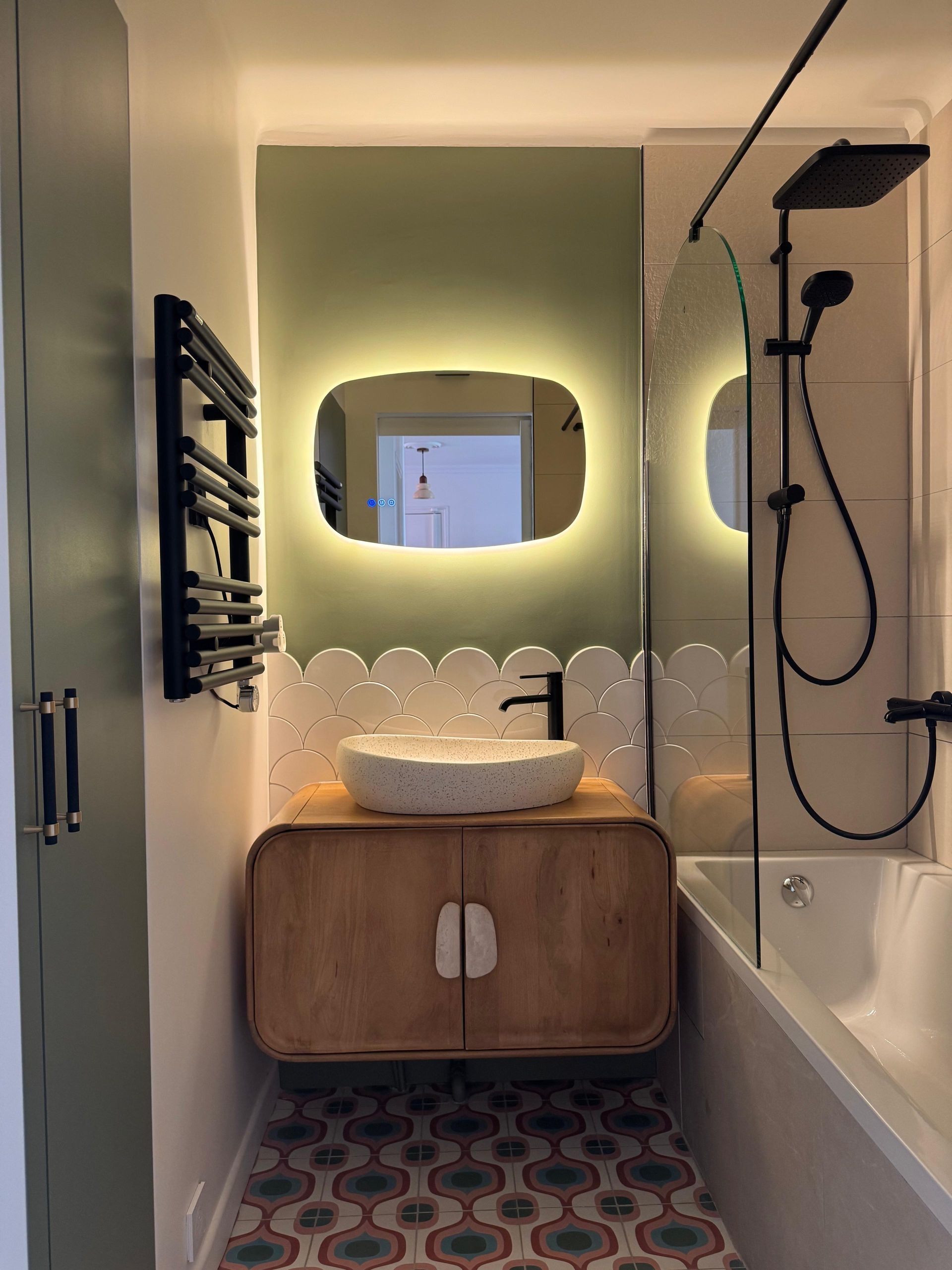 Salle de bains moderne avec vanité blanche, mur carrelé bleu et douche en verre.
