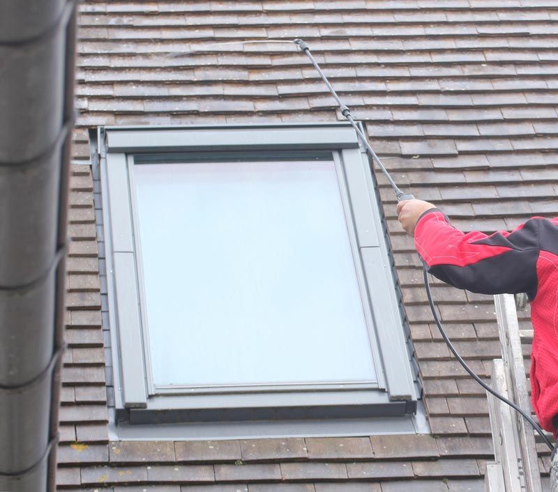 Gros plan sur un ouvrier qui passe le nettoyeur à haute pression sur un toit