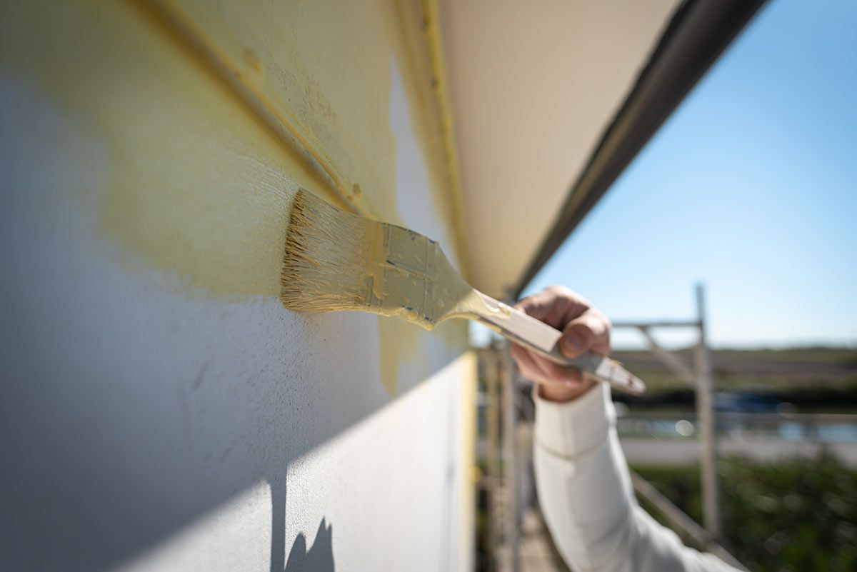 Gros plan sur une personne qui peint une façade en jaune