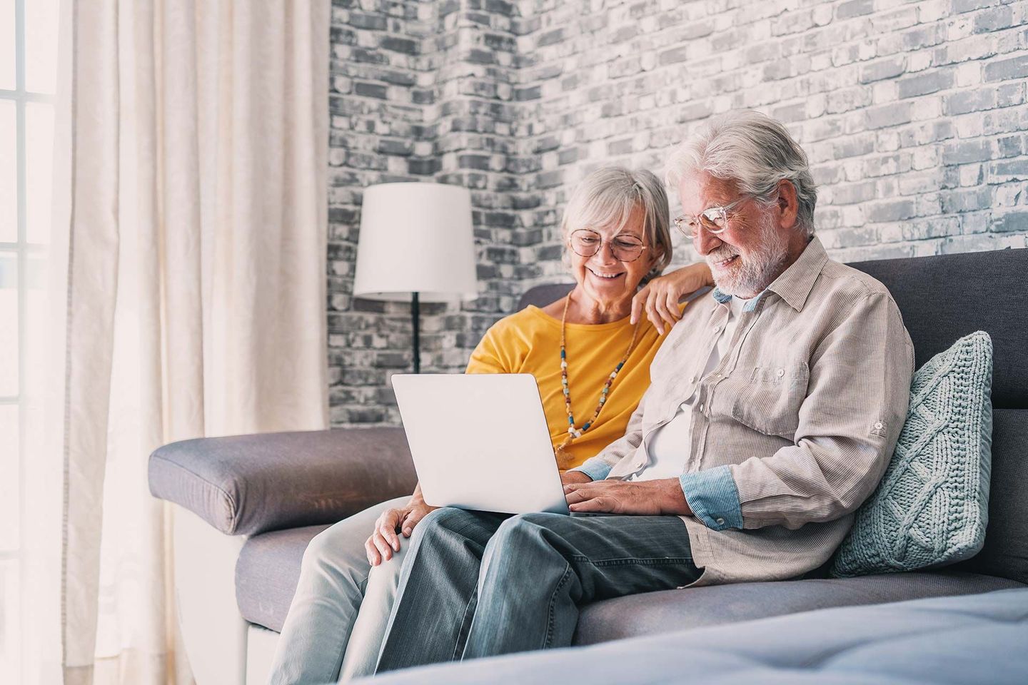 Couple de personnes âgées dans un canapé avec un ordinateur