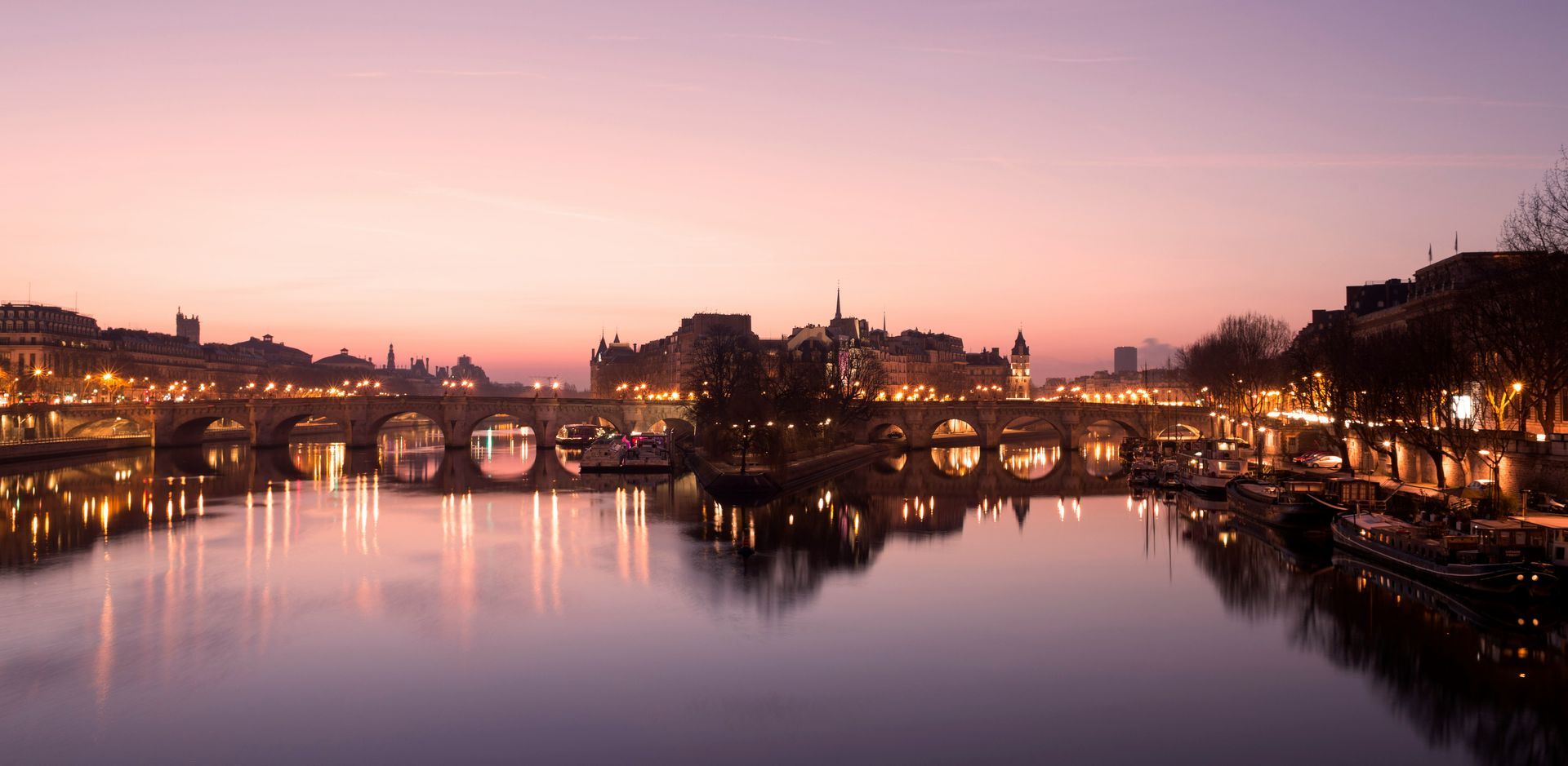 The Seine, the Parisian river, is lit at sunset with all the Hausmanian buildings.