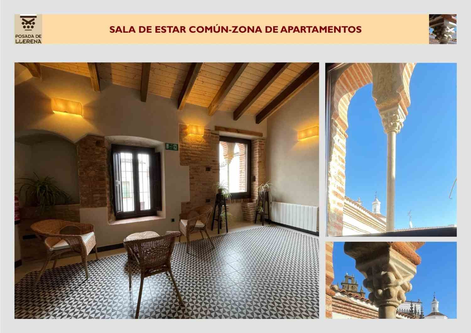 Sala de estar común de un apartamento rústico, con suelo de baldosas, vigas de madera, paredes de ladrillo.
