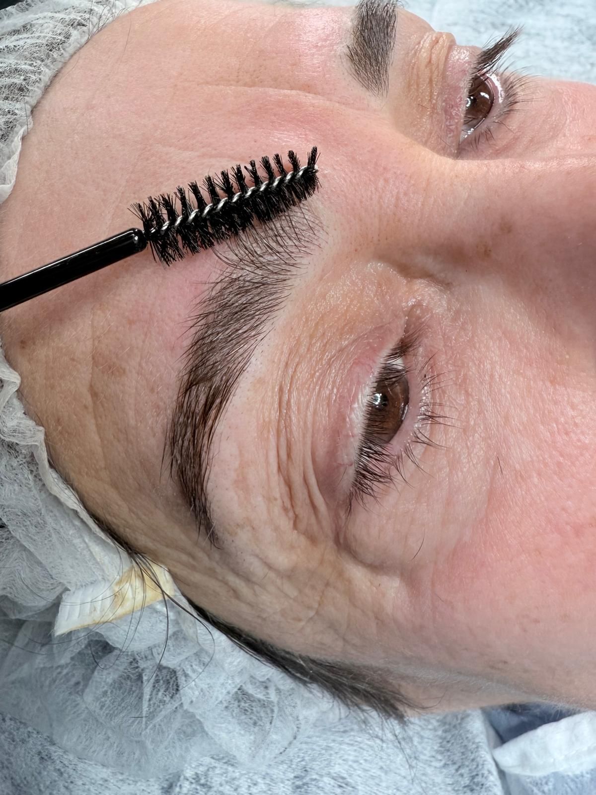 Una mujer se está depilando las cejas con un cepillo.