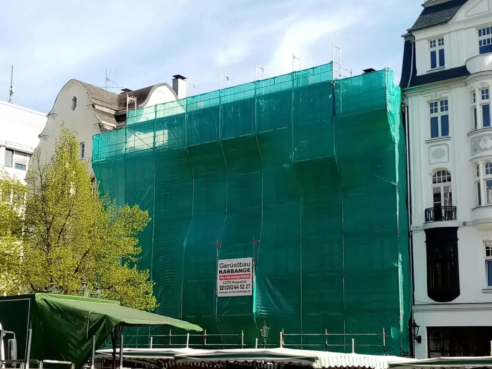 Ein Gebäude mit Gerüst wird vom Mike Karbange Gerüstbau umgebaut.