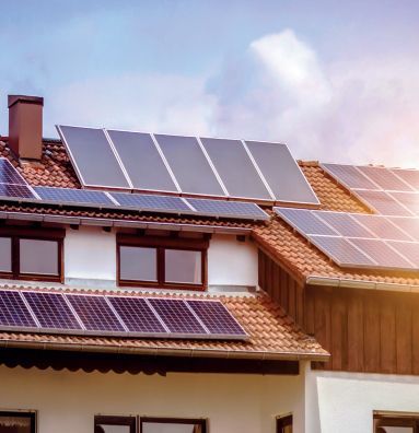 Paneles solares en el tejado de una casa con tejas bajo un cielo parcialmente nublado.