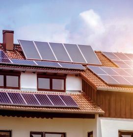Paneles solares en el tejado de una casa con tejas bajo un cielo parcialmente nublado.