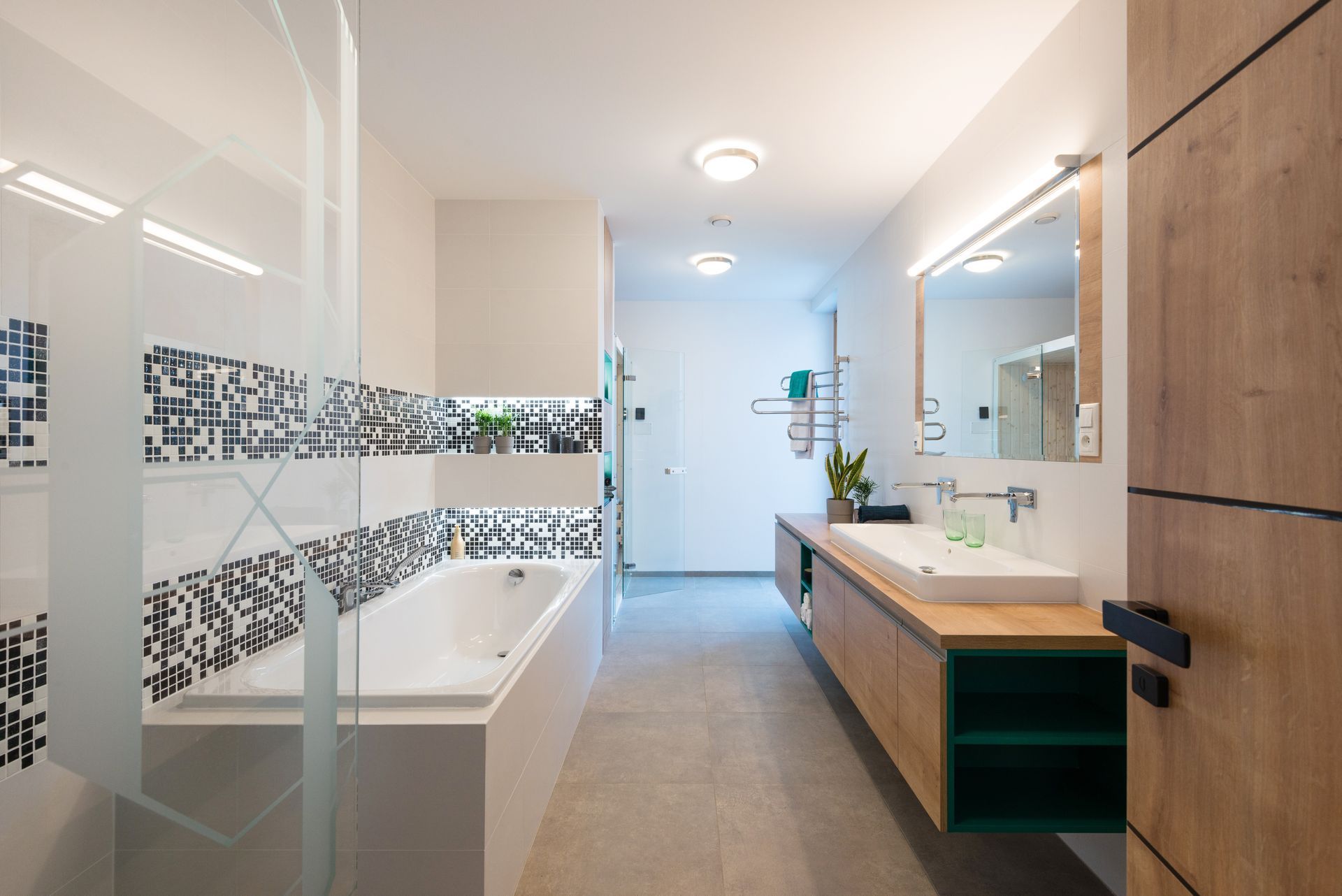Salle de bains moderne avec douche vitrée, baignoire, lavabo et meuble en bois et carrelage au sol et aux murs.