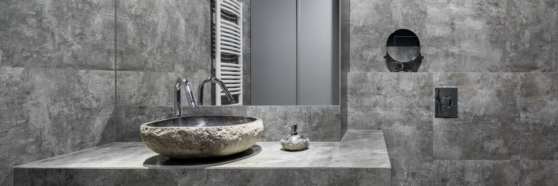 Salle de bains moderne grise avec un lavabo en pierre, un miroir et un sèche-serviettes.