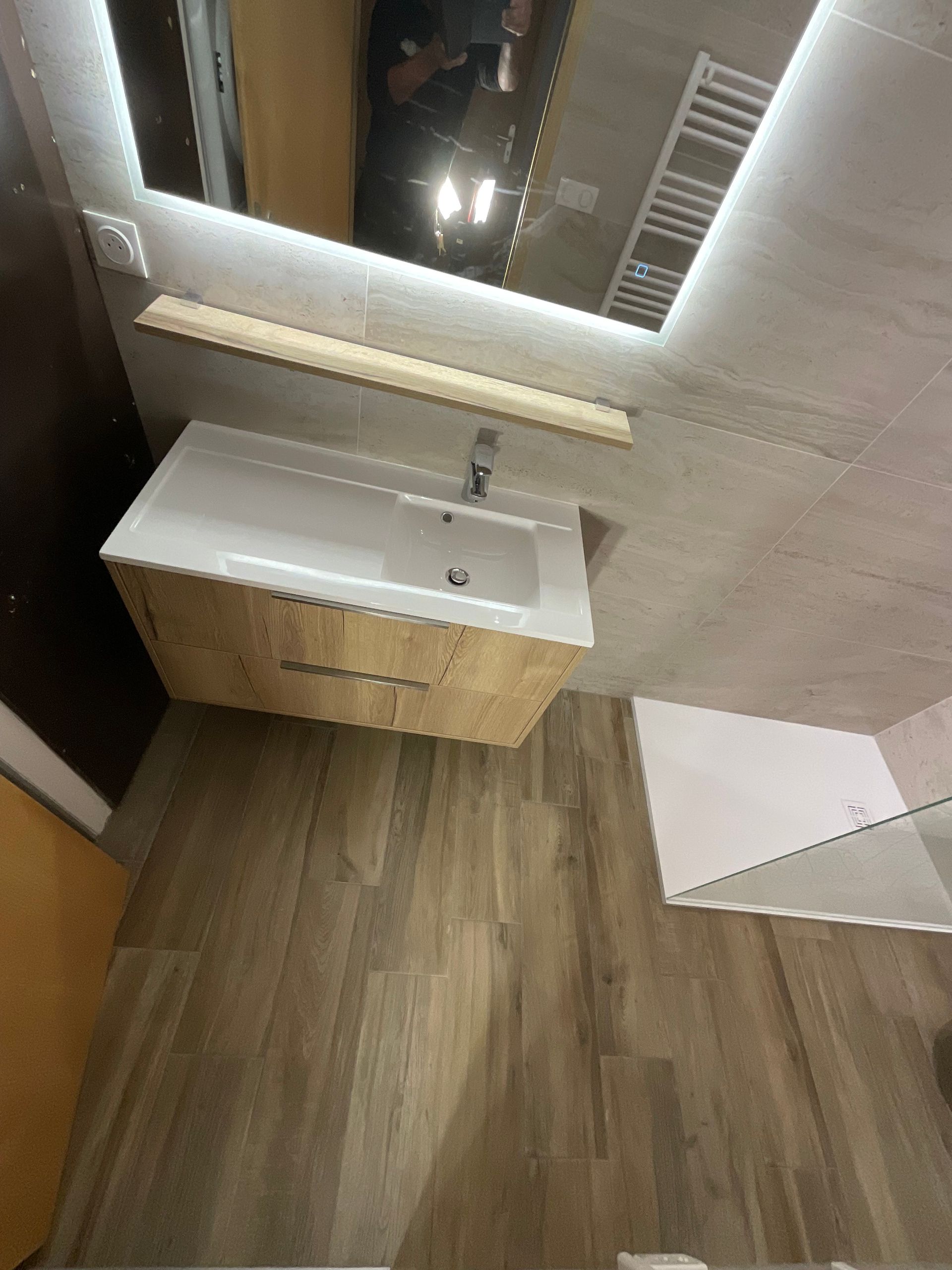 Lavabo compact avec évier et miroir, sol imitation bois.