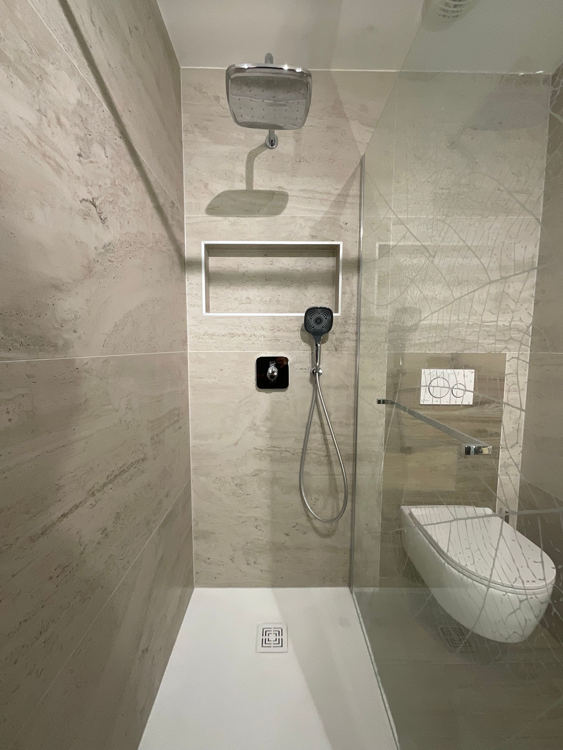 Cabine de douche à l'italienne avec carrelage mural moderne et WC suspendus à côté