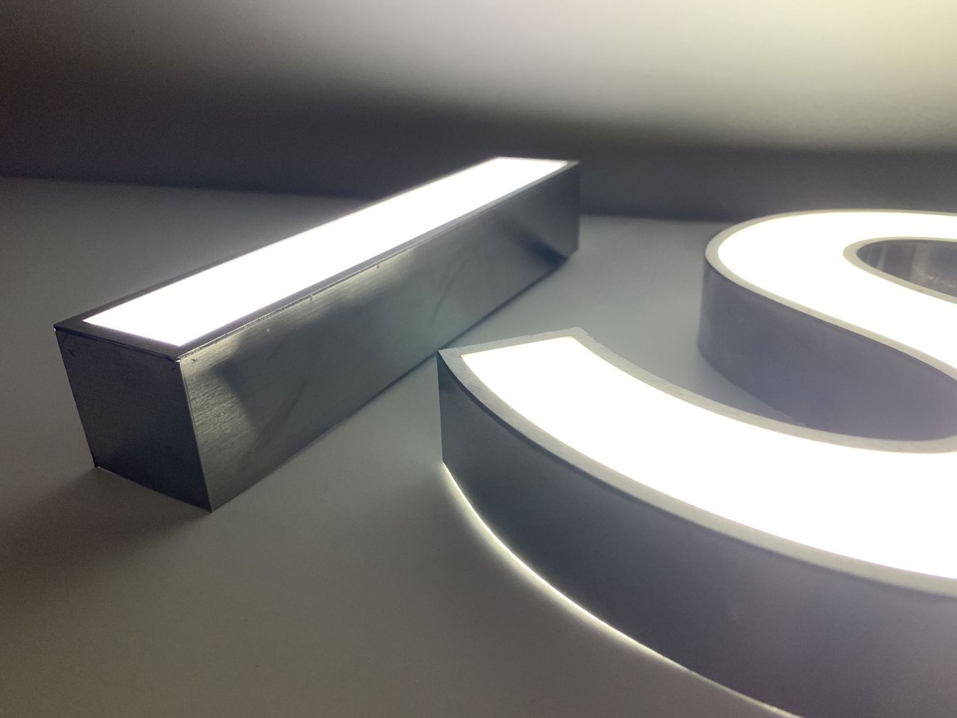 Zoom sur deux lettres lumineuses I et S en atelier.