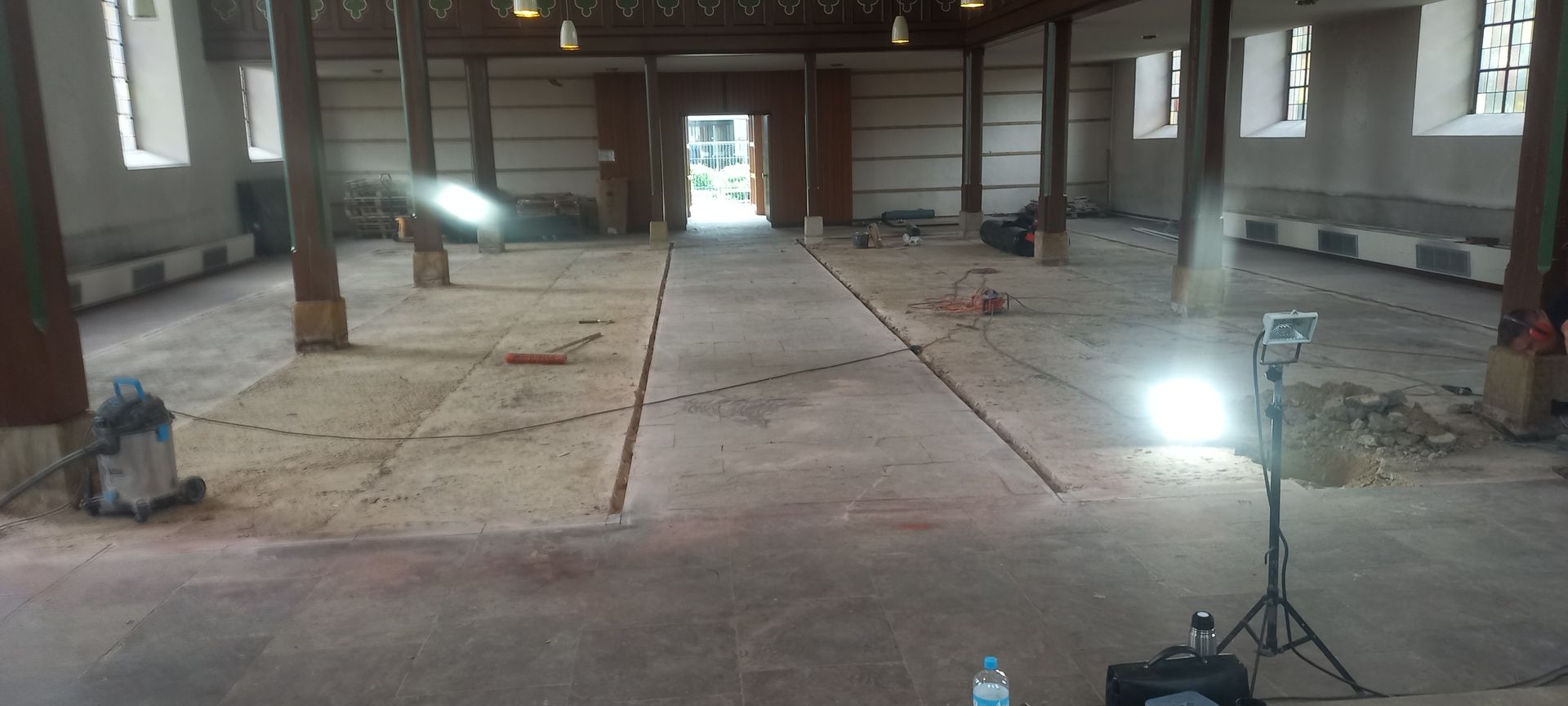 Ein großer leerer Raum mit vielen Fenstern und Lichtern auf dem Boden.