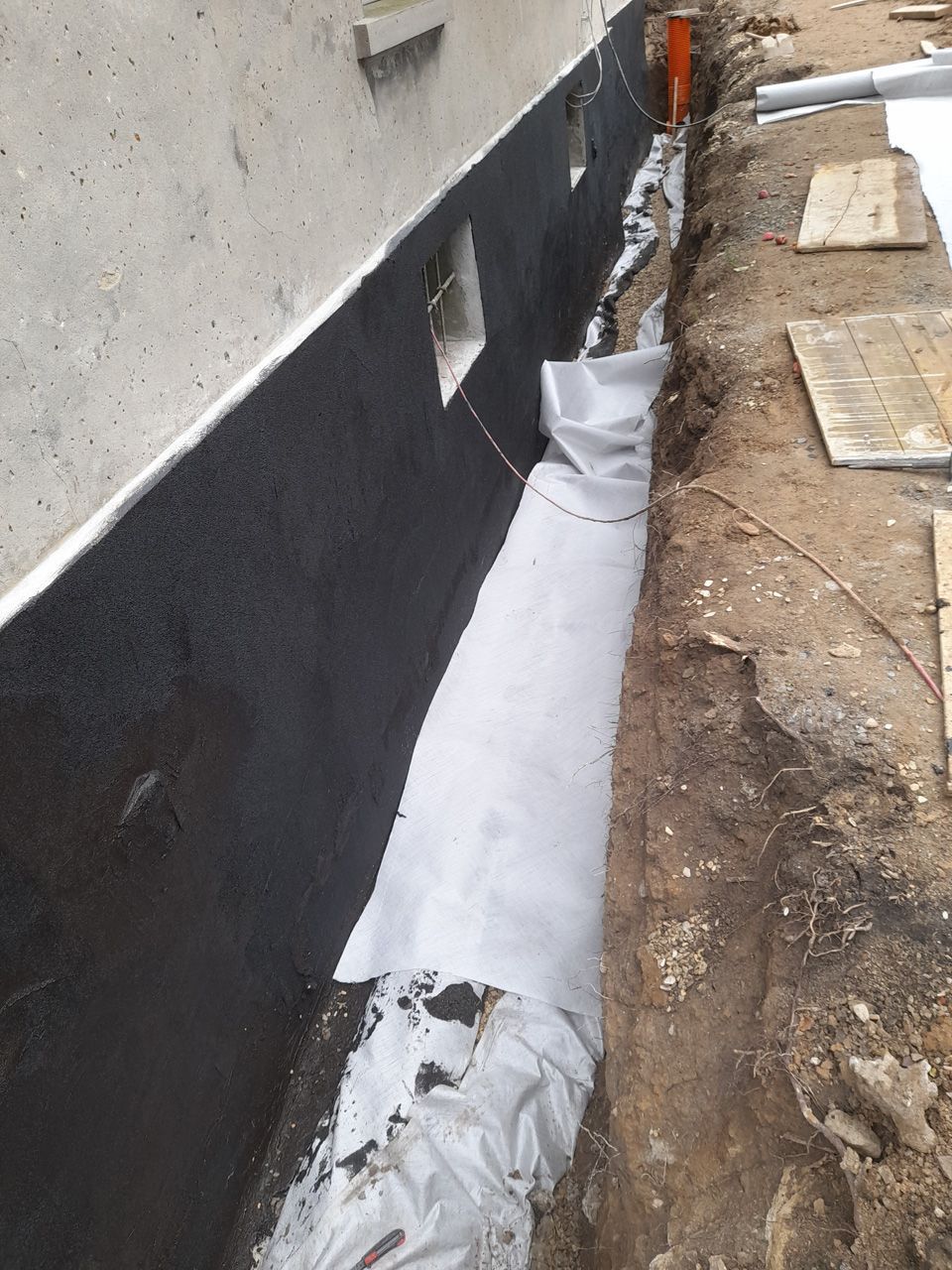 An der Seite eines Gebäudes wird ein Entwässerungssystem installiert.