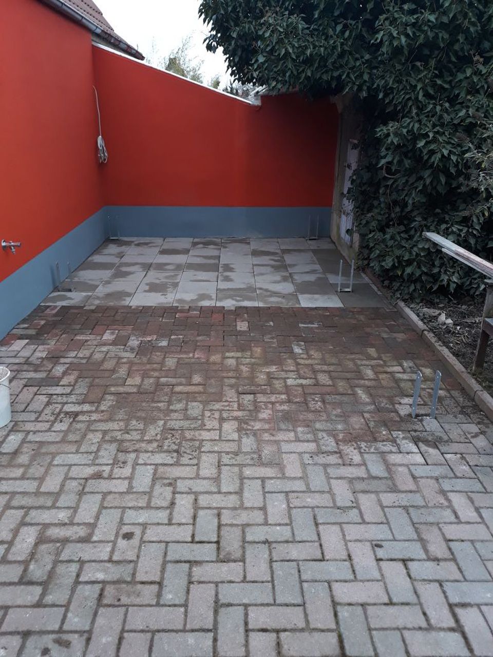 Eine gemauerte Auffahrt mit einer roten Wand im Hintergrund.