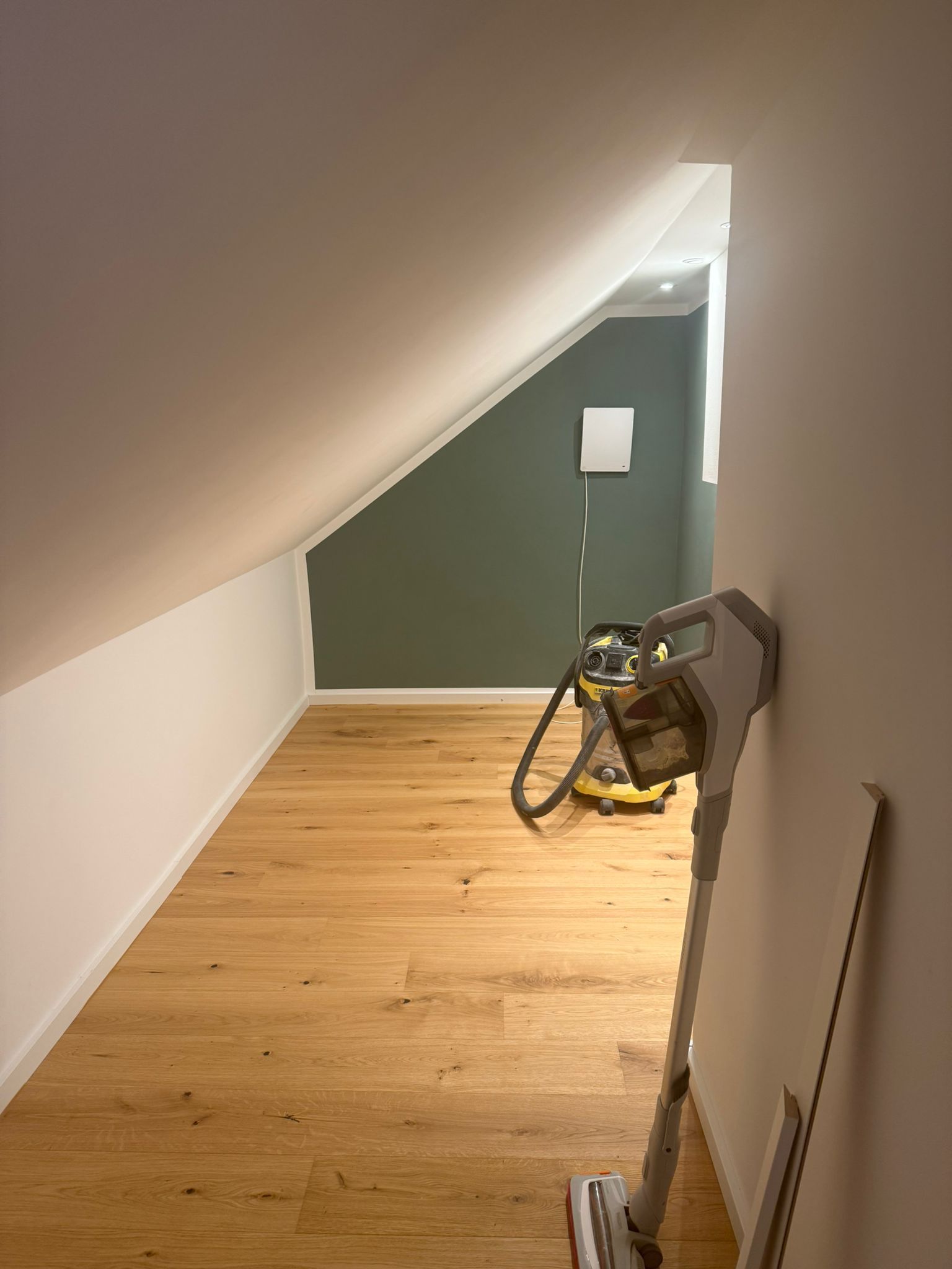 Auf einem Dachboden steht ein Staubsauger auf einem Holzboden.