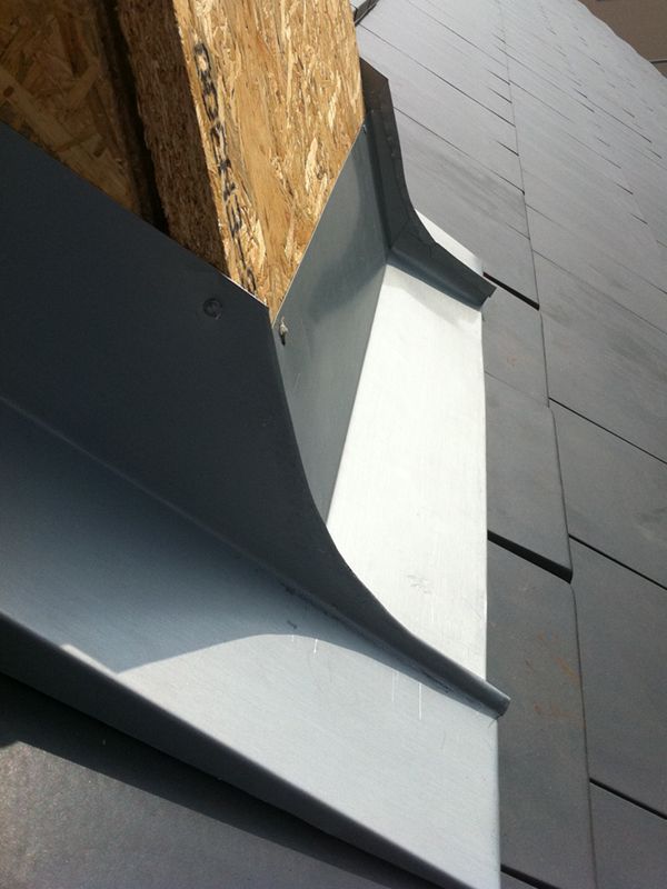 Graue Metallverkleidung an der Gebäudeaußenseite, angrenzend an Holz.