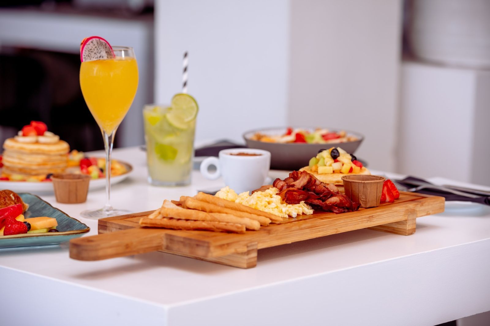 Een houten snijplank gevuld met eten en drinken op een tafel.