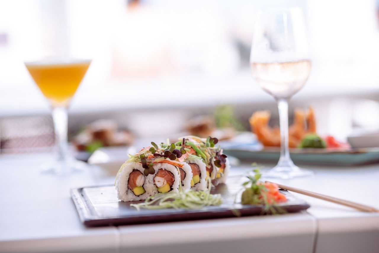A plate of sushi and a glass of wine on a table.