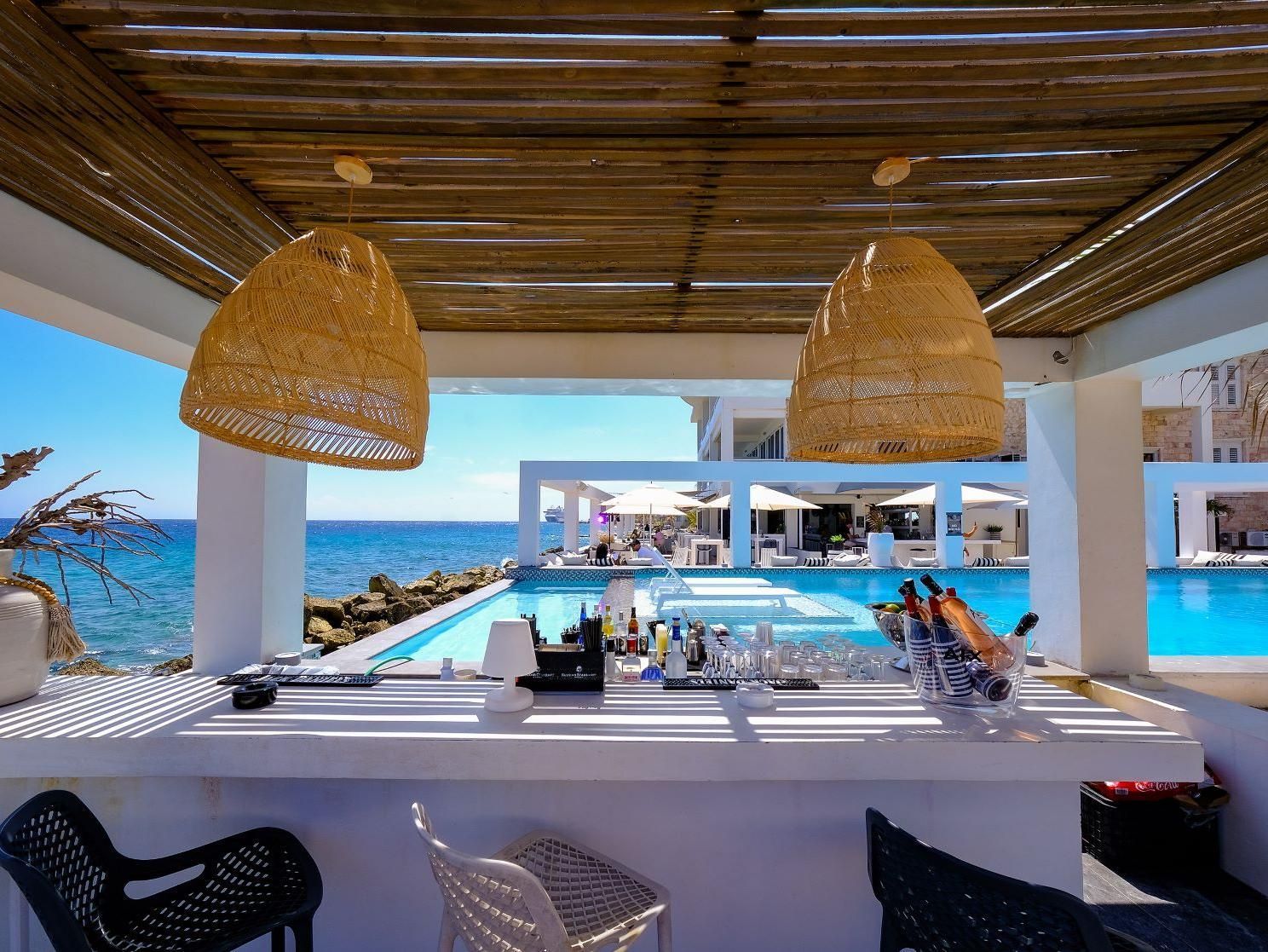 A bar with a view of the ocean and a swimming pool