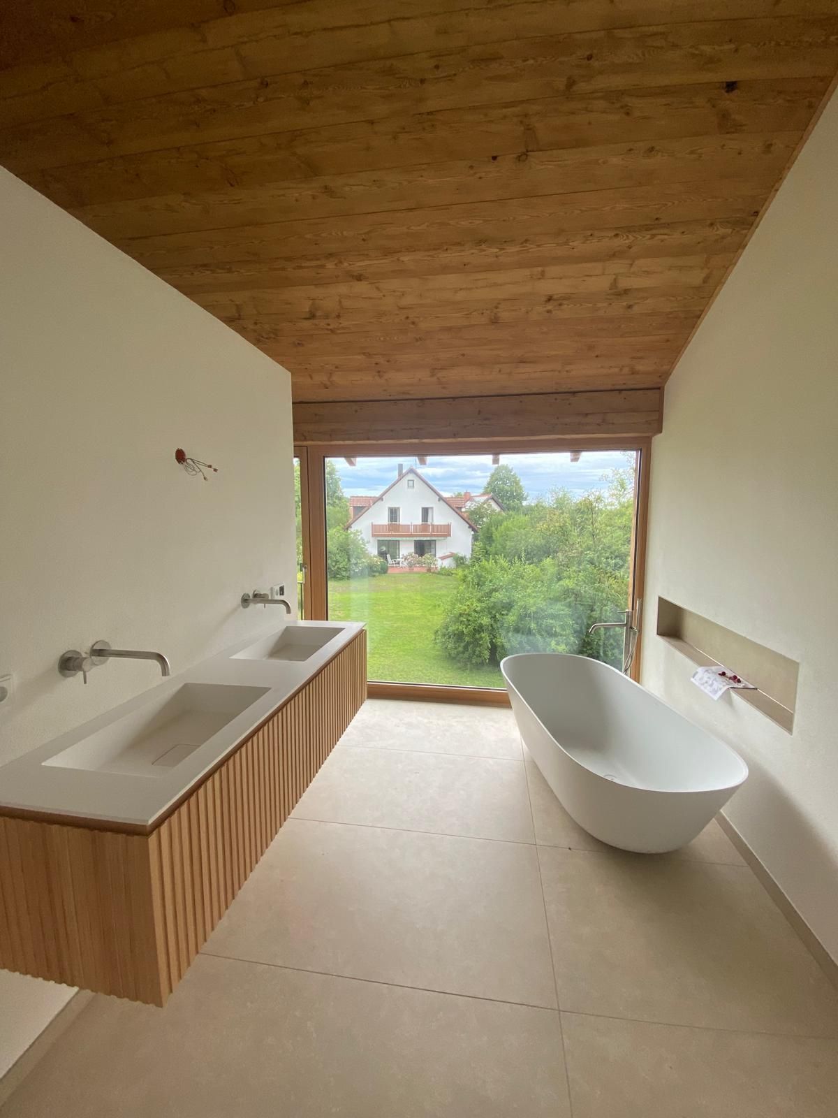 Modernes Badezimmer mit Holzdecke, schwebendem Waschbecken, freistehender Badewanne und Blick in den Garten