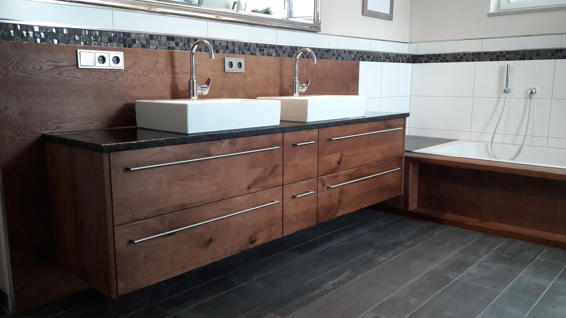 Modernes Badezimmer mit einem Waschtisch aus dunklem Holz, zwei Waschbecken und weiß gefliesten Wänden