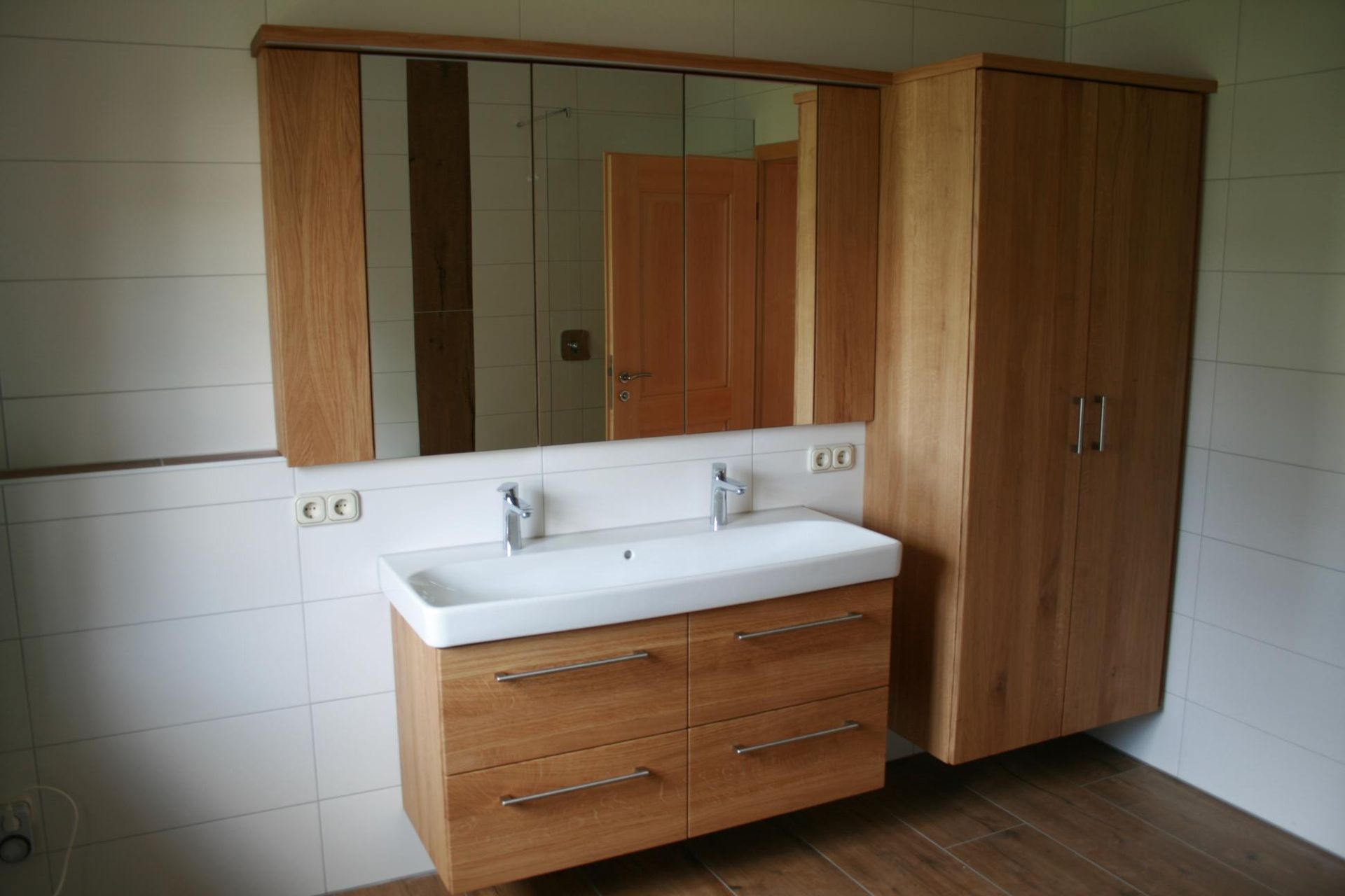 Badezimmer mit Doppelwaschtisch, Spiegelschrank und Holzschrank in einem gefliesten Raum